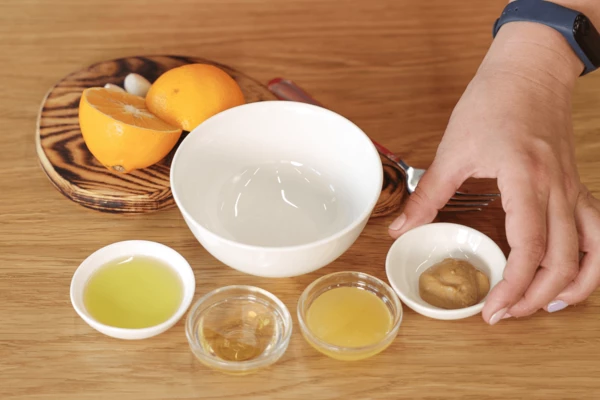 Приготовить заправку: в чашке смешать горчицу, лимонный сок, винный уксус, оливковое масло, мед и натертый чеснок. 