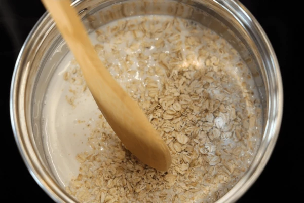 В сотейник влить кокосовое молоко, всыпать овсянку, варить до готовности.
