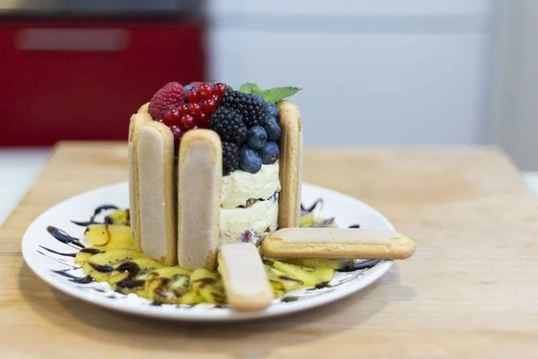 Готовое тирамису выньте из холодильника, снимите форму, аккуратно разрезав ножницами сбоку. По всему периметру плотно прикрепите  печенье савоярди, чтобы получился "колодец". Украсьте ягодами по своему вкусу.