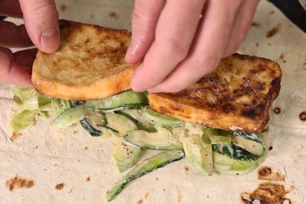 Айсберг, огурец и авокадо нарезать ломтиками, смешать с ореховым соусом и выложить на лаваш. Сверху выложить тофу.