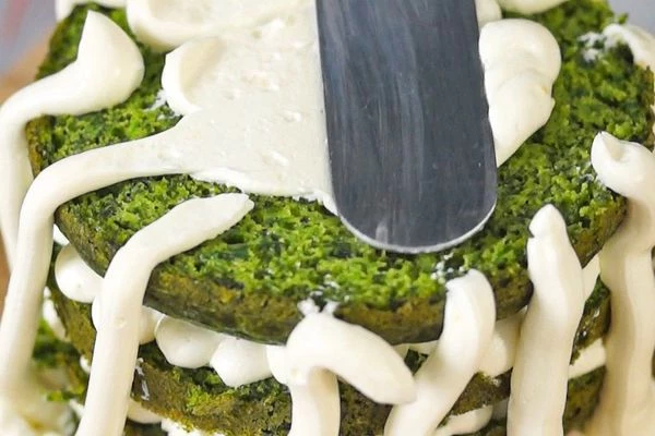 По внешнему краю коржа отсадить крем, в середину выложить нарезанные огурцы. Слои повторить. Бока торта покрыть кремом и выровнять.