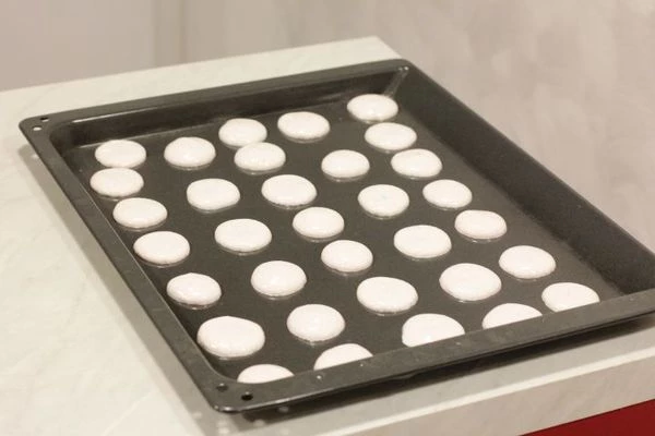 На  противень застелите промасленную бумагу для выпекания. Выдавите из кондитерского мешка небольшими порциями миндальную массу, чтобы получились кружки диаметром примерно 4см.