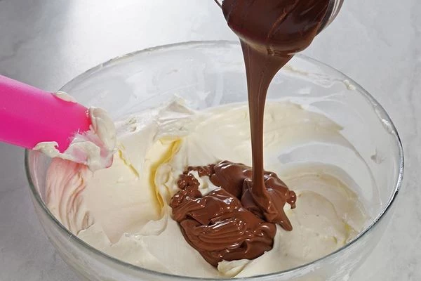 Разделить крем на 2 части. Одну часть поставить в холодильник, в другую ввести растопленный в микроволновке шоколад и еще раз хорошо перемешать.