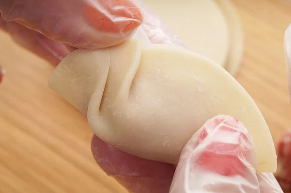 Еще один вариант заворачивания пельменей, типа "гедза". Смочить край теста водой и начать защипывать с одного края складочки.