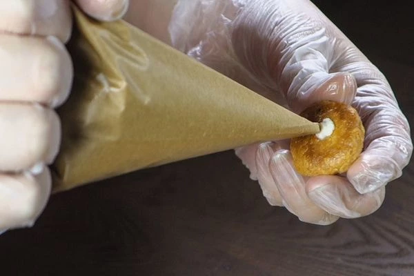 В готовых профитролях шпажкой проделать дырку, заполнить пирожные кремом (можно разрезать пополам и смазать серединку кремом).