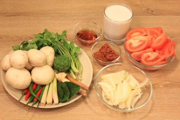 Лук нарезать на 4 части. Помидоры  - на дольки. Галангал нарезать пластинками, лемограсс слегка раздавить ножом, разрезать на 2 части. Шампиньоны разрезать на 4 части, если крупные, то на 6-8 частей.