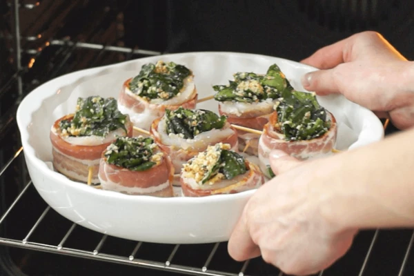 Форму для запекания застелить пергаментом. Рулетики поставить в форму в вертикальном положении. Выпекать в предварительно разогретой до 185 градусов духовке 20 минут.
