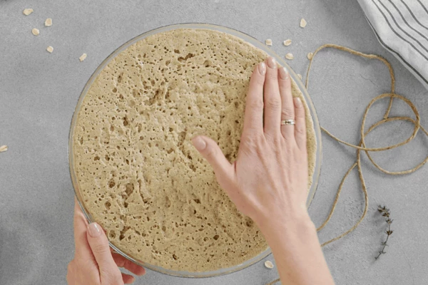 Поставить в теплое место для расстойки. Когда тесто увеличится в объеме в 2 раза (примерно через 1 час), обмять его. 