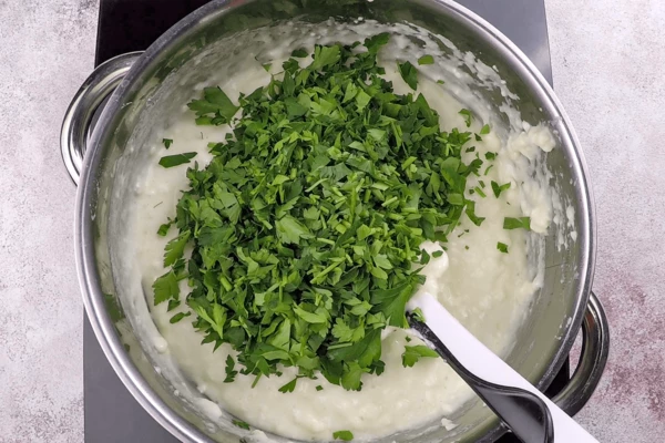 Выключить огонь, добавить нарезанную зелень.