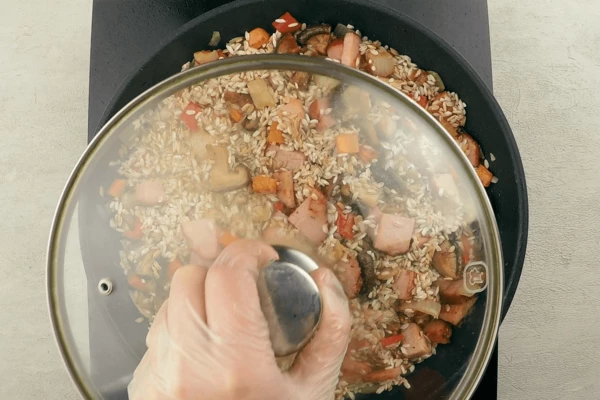 Влить воду, добавить соль и специи. Накрыть крышкой и потушить на слабом огне примерно 40 минут. Рис должен распариться, но не перевариться.