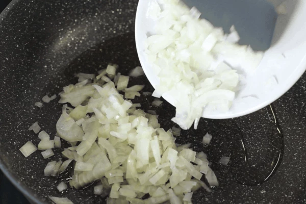 В сковороду налить масло, выложить лук и обжарить до прозрачности. Затем добавить чеснок, обжарить в течение минуты.