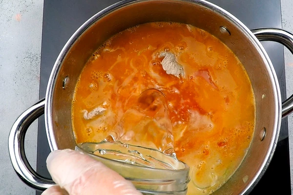 Добавить помидоры, лавровый лист и 2 стакана воды. Варить на сильном огне около 30 минут. 