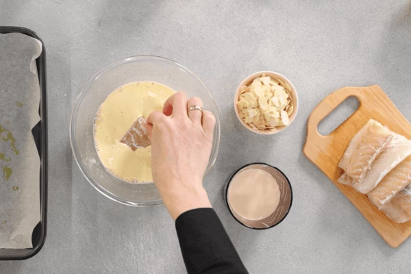 Треску разморозить, обсушить салфеткой, нарезать каждый кусочек пополам. Каждый кусочек рыбы обмакнуть в яичную массу.
