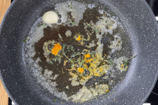 Апельсин вымыть, снять цедру. На сковороду выложить сливочное масло, растопить на медленном огне. Затем добавить листья тимьяна и цедру апельсина. 