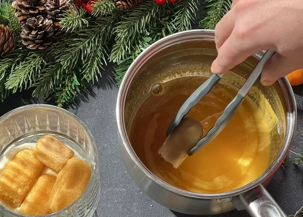 На дно креманки выложить немного крема. Печенье савоярди разломать пополам, обмакнуть сахарной стороны в мандариновый сироп. Выложить печенье сверху крема.