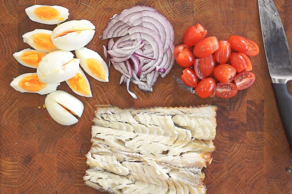  Яйца отварить, очистить, нарезать на 4 части. Помидоры нарезать на 2 половинки, лук нарезать тонкой соломкой. Треску очистить от кожи и хребта.