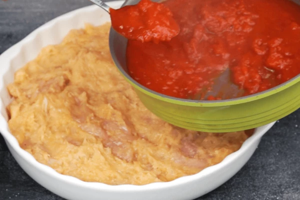 "Собрать" пиццу: в форму с глубокими краями (у нас диаметр 24 см, высота 5 см) выложить основу из пробитого куриного филе, в один слой, затем соус.