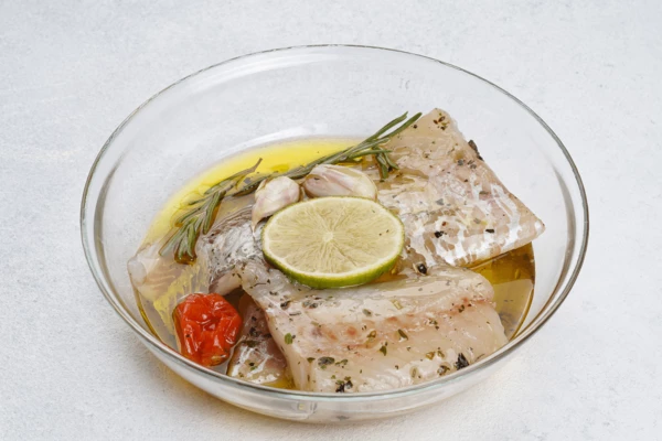 Филе трески замариновать в оливковом масле с розмарином, дольками раздавленного чеснока, специями, ломтиком лайма и помидором черри.