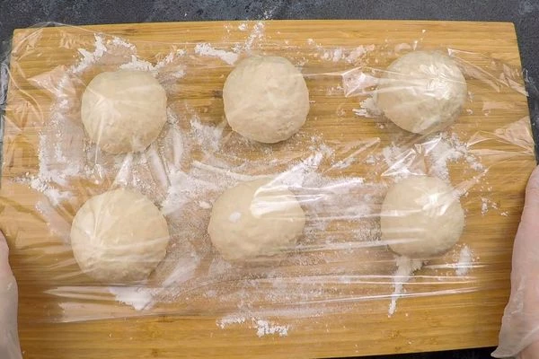 Разделить тесто на 6 равных частей, скатать в шары, накрыть пищевой пленкой и оставить в теплом месте примерно на 1 час.