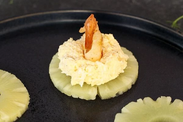 Кольца ананаса выложить на блюдо для подачи. 
Из смеси яиц, сыра и майонеза сформировать шарики и выложить их в центр колец ананаса. 
Сверху выложить креветки. 