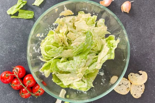 Айсберг вымыть, обсушить, порвать средними кусочками, смешать с соусом Цезарь.