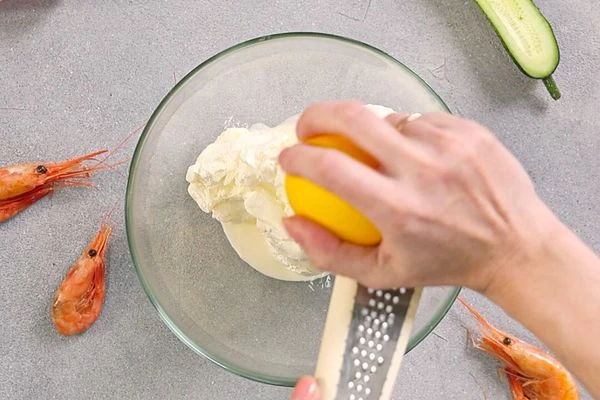 Творожный сыр комнатной температуры взбить с охлажденными сливками, добавить остатки цедры лимона, перемешать, выложить в кондитерский мешок с насадкой.
