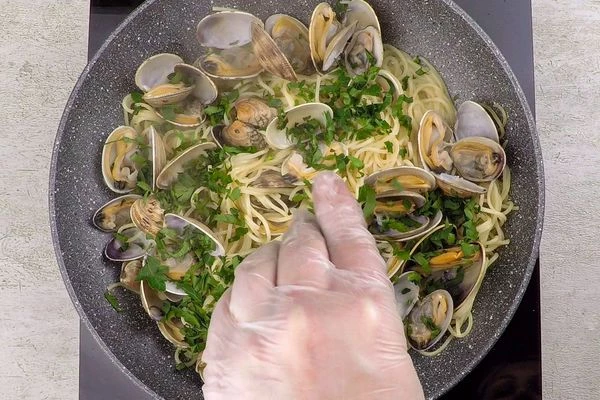 Удалить чеснок, перец и розмарин — они уже отдали свой вкус в масло. Прогреть пасту, помешивая 2-3 минуты. Затем добавить мелко нарезанную зелень. Снять с огня.