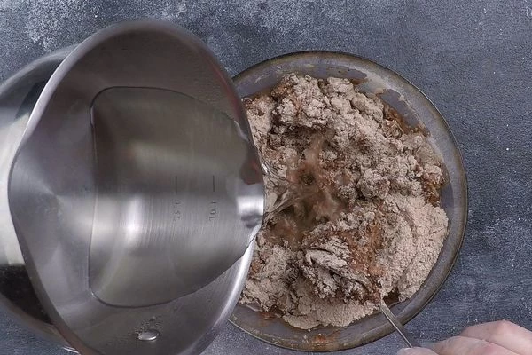 В мучную смесь влить кипяток, быстро перемешивая тесто.