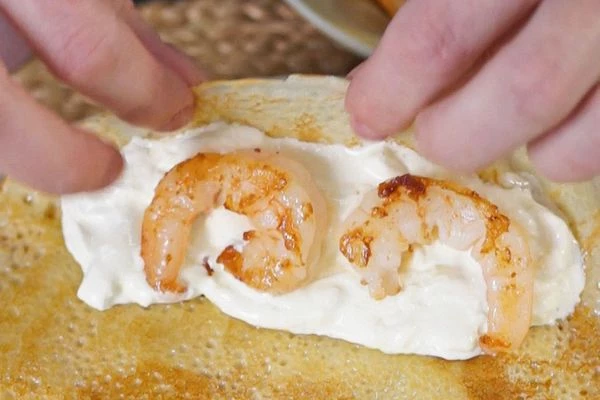 На край блинчика выложить страчателлу и пару креветок, свернуть в трубочку. Повторить с оставшимися блинами. Готовые блины выложить на тарелку для подачи. 