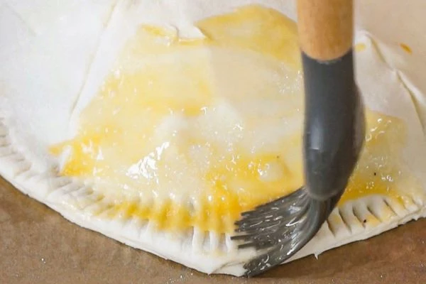 Смазать тесто взбитым яйцом. 