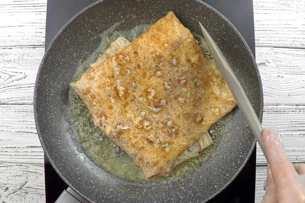 Завернуть лаваш в виде конверта, перевернуть на другую сторону, увеличив огонь, обжарить до золотистого цвета, чтобы сыр расплавился, а белок схватился.