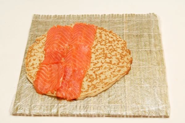  Нарезать слабосолёную сёмгу тонкими пластами и выложить рыбу сплошным слоем примерно на половину блина

 