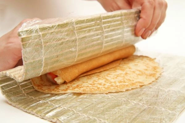 С помощью коврика свернуть блин рулетом, лёгким давлением пальцев распределить начинку равномерно

 