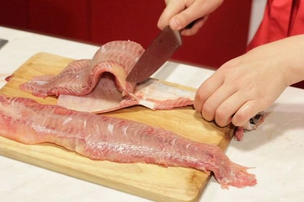 Отрезать голову, разрезать на 2 пласта вдоль кости. Начиная с хвостовой части срезать кожу и  реберные кости. Чистое филе нарезать кубиками примерно 2х2 см.