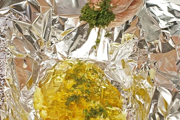 В форму для запекания выстелить фольгу, в центр фольги положить несколько ложек меда, тертый имбирь, зелень.