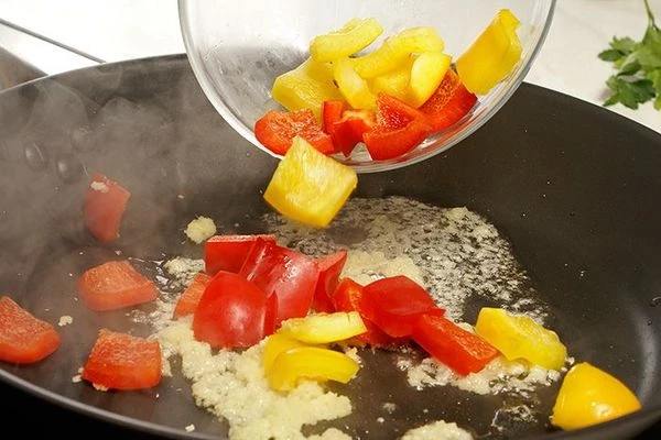 Затем добавить нарезанный перец, обжаривать 1-2 минуты.