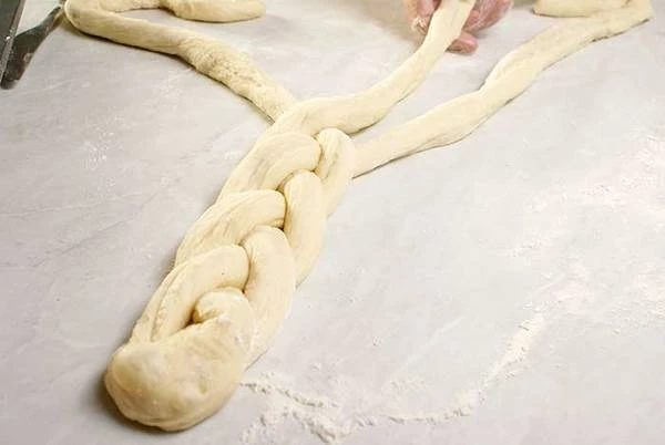 Из второй части теста скатать  толстую колбаску, разрезать ее на 3 полоски. Каждую полоску скатать в виде жгутика,  "заплести" в виде косички.