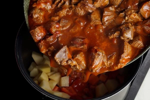 Овощи переложить в мультиварку, сверху обжаренное мясо с томатом. Посолить по вкусу, добавить специи.