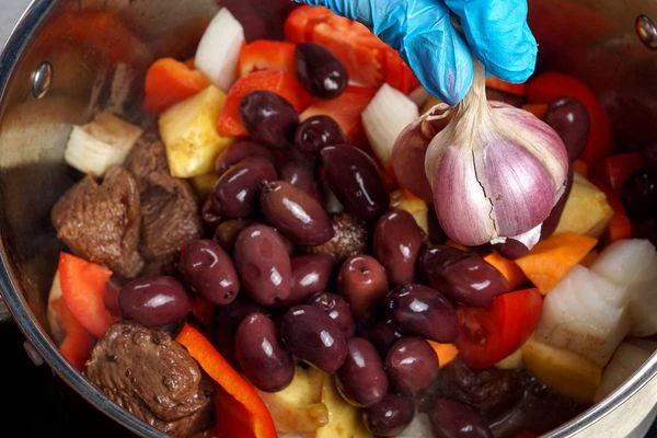 Добавить овощи, оливки, специи, влить еще 1ст воды и потушить около 30 минут.