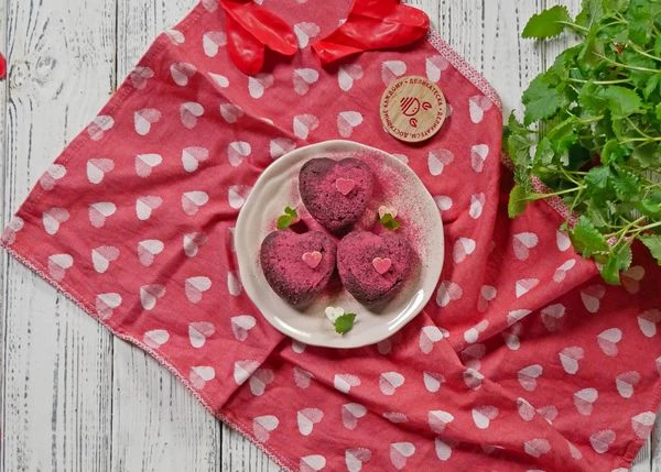 100 г белого шоколада растопить на водяной бане. Распределить по форме с маленькими сердечками, дать застыть. 
Остывший брауни выложить на тарелку. Оформить сердечками из белого шоколада и мелиссой. Посыпать пудрой из малины. Приятного аппетита!
