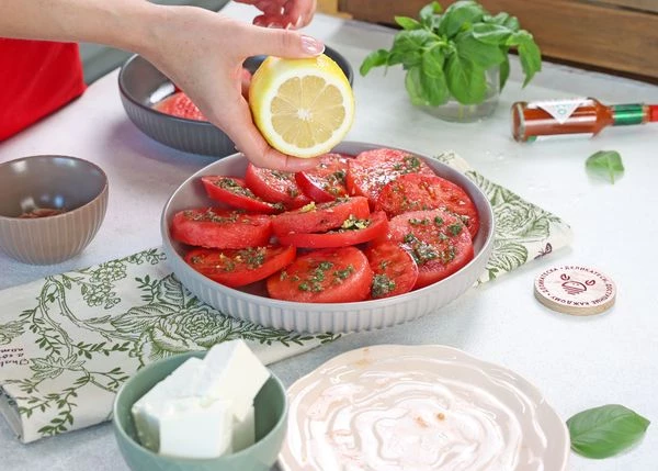 Соусом из анчоусов смазать ломтики арбуза и томатов. Добавить цедру и сок лимона. 