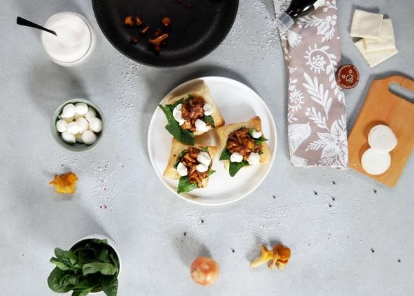 Выложить на слойки листья шпината, обжаренные лисички и ломтики моцареллы. 