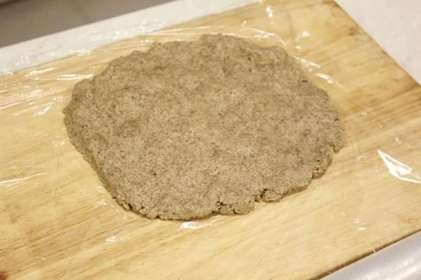 На доску застелить пищевую пленку. В центр пленки выложить хлебно-сметанную массу и разровнять в виде прямоугольника.