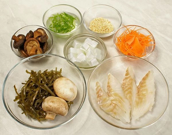 Водоросли вакаме или морскую капусту размочить в холодной кипяченой воде 15-20 минут. Морковь и лук зеленый нарезать тонкой соломкой. Творог тофу нарезать небольшими кубиками. Грибы шиитаки размочить в теплой воде 1-2 часа, затем слить воду, залить свежей водой и проварить 20-30 минут. Филе рыбы нарезать тонкими ромбиками.