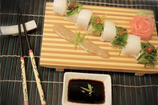 С полученных 8 роллов снять пищевую пленку. Выложить на блюдо через один: зеленый - белый, зеленый - белый. Украсить красной икрой, рядом нарисовать прямо на блюде полоску орехового соуса. Подавать с имбирем и васаби.