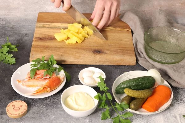 Зеленый горошек бланшируйте  в течение 30 секунд в кипящей подсоленной воде с соком лимона. Затем переложите в воду со льдом до полного остывания. Воду слейте.  Овощи и яйца отварите. Картофель нарежьте кубиками — 0,5х0,5 см. Переложите в глубокую тарелку.