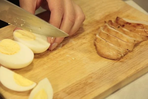 В салатнике смешать салат, необходимое количество соуса по вашему вкусу. Украсить половинками помидора, яйцом, тертым сыром, гренками. Рядом выложить нарезанную куриную грудку.