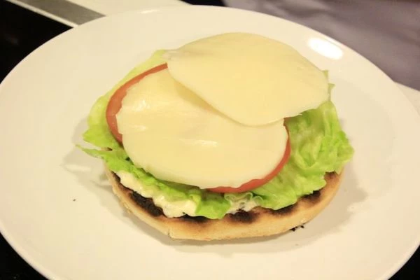 Сыр нарезать тонкими пластиками. Выложить на помидор.