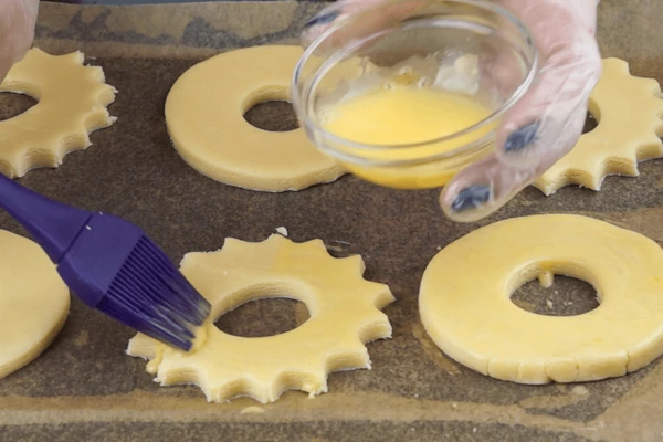 Желток смешать с водой и смазать коржики. 