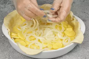 Картофель очистить, нарезать тонкими пластиками (кружочками), лук нарезать кольцами. Выложить на дно теста картофель, затем лук.